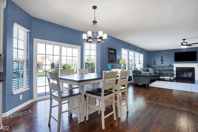 13836 Fieldcrest Dr, Mccordsville, IN 46055 - dining space with dark wood-style flooring, baseboards, visible vents, ceiling fan with notable chandelier, and a fireplace