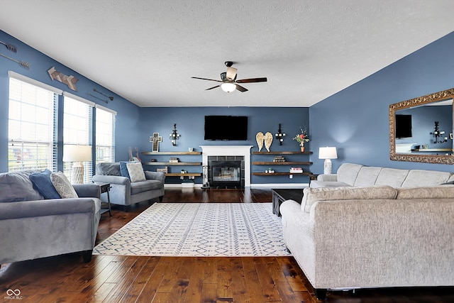 13836 Fieldcrest Dr, Mccordsville, IN 46055 - living area with a tiled fireplace, a ceiling fan, a textured ceiling, and dark wood-type flooring