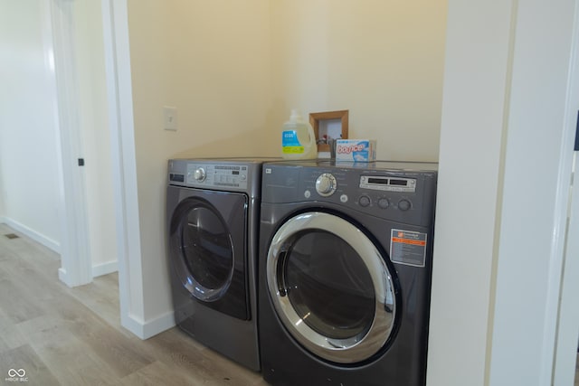 2302 Prospect St, Indianapolis, IN 46203 - clothes washing area with light wood finished floors, washing machine and clothes dryer, baseboards, and laundry area