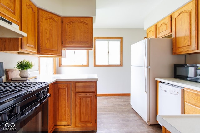 4917 Algonquin Trl, Kokomo, IN 46902 - kitchen with black appliances, under cabinet range hood, light countertops, light wood-style flooring, and baseboards