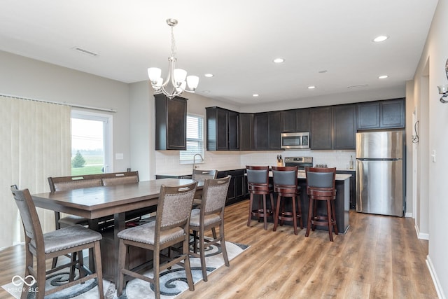 dining space with a chandelier, visible vents, light wood finished floors, and plenty of natural light