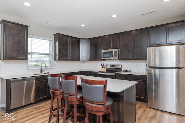 kitchen with recessed lighting, a sink, stainless steel appliances, light wood-style flooring, and dark brown cabinets