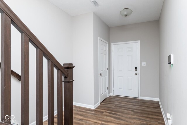 entrance foyer featuring dark wood-style floors, stairs, visible vents, and baseboards