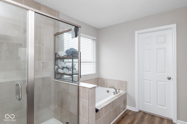 bathroom with a stall shower, a garden tub, and wood finished floors
