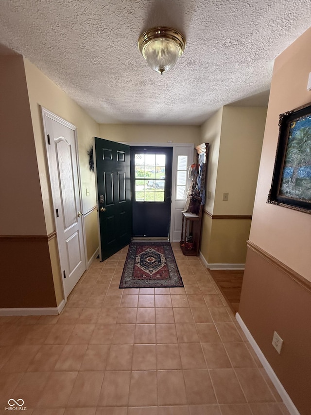 entryway with baseboards, a textured ceiling, and light tile patterned floors