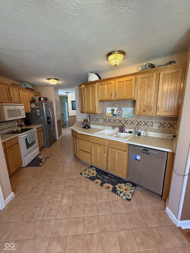 kitchen with stainless steel appliances, light countertops, light tile patterned floors, a sink, and decorative backsplash