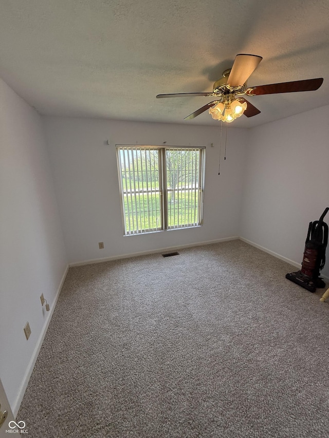 carpeted empty room with a textured ceiling, visible vents, a ceiling fan, and baseboards
