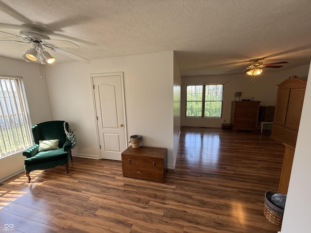 living area with ceiling fan, baseboards, wood finished floors, and a textured ceiling