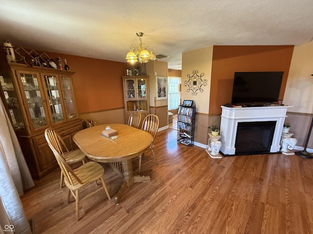dining space with an inviting chandelier, visible vents, light wood-type flooring, baseboards, and a fireplace