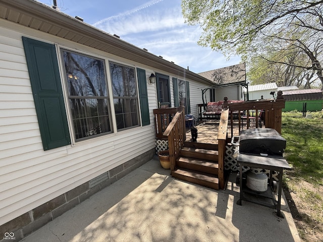 deck with a patio area, a grill, and fence
