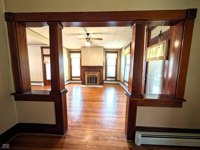 4335 River Rd, Columbus, IN 47203 - unfurnished living room featuring baseboard heating, wood-type flooring, a ceiling fan, and a fireplace with flush hearth