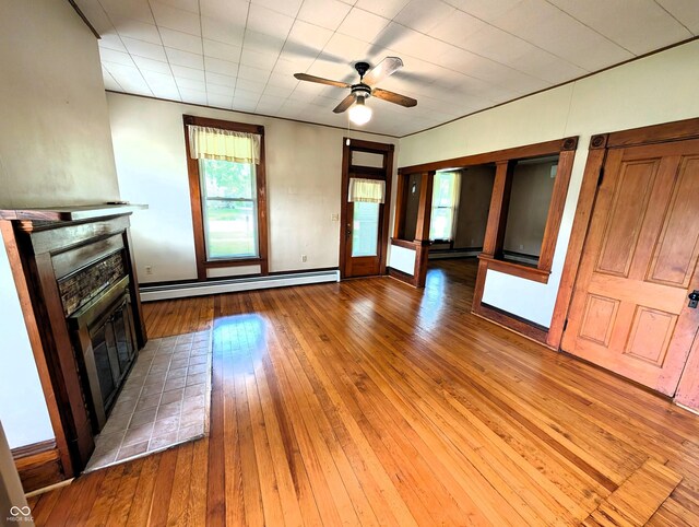 4335 River Rd, Columbus, IN 47203 - unfurnished living room with a baseboard radiator, a glass covered fireplace, hardwood / wood-style floors, and a ceiling fan