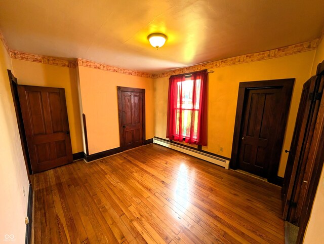 4335 River Rd, Columbus, IN 47203 - unfurnished bedroom with baseboard heating, hardwood / wood-style flooring, and baseboards
