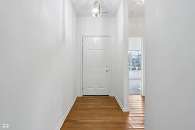 hall featuring baseboards, wood finished floors, and visible vents