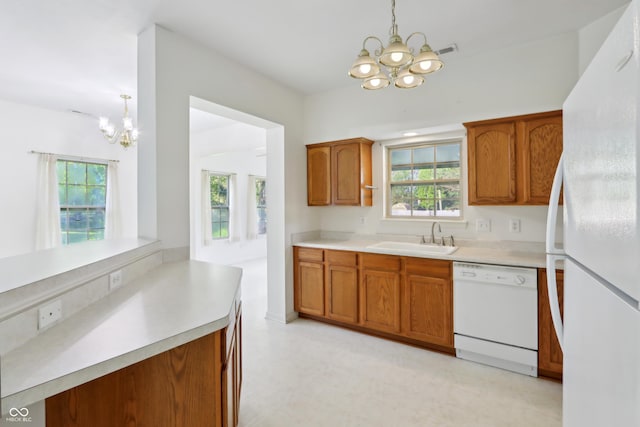 kitchen featuring white appliances, a chandelier, brown cabinetry, and a sink