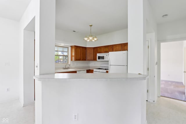 kitchen featuring a sink, light countertops, white appliances, and a notable chandelier