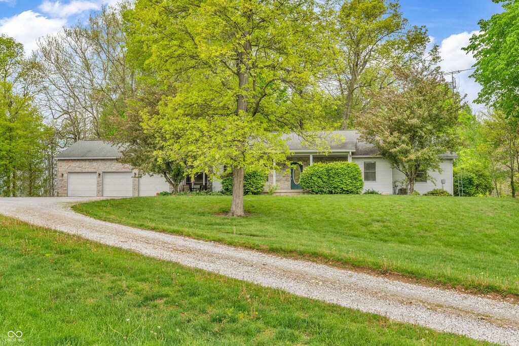 10154 S County Road 10 E, Cloverdale, IN 46120 - obstructed view of property featuring driveway, a front lawn, a garage, and stone siding