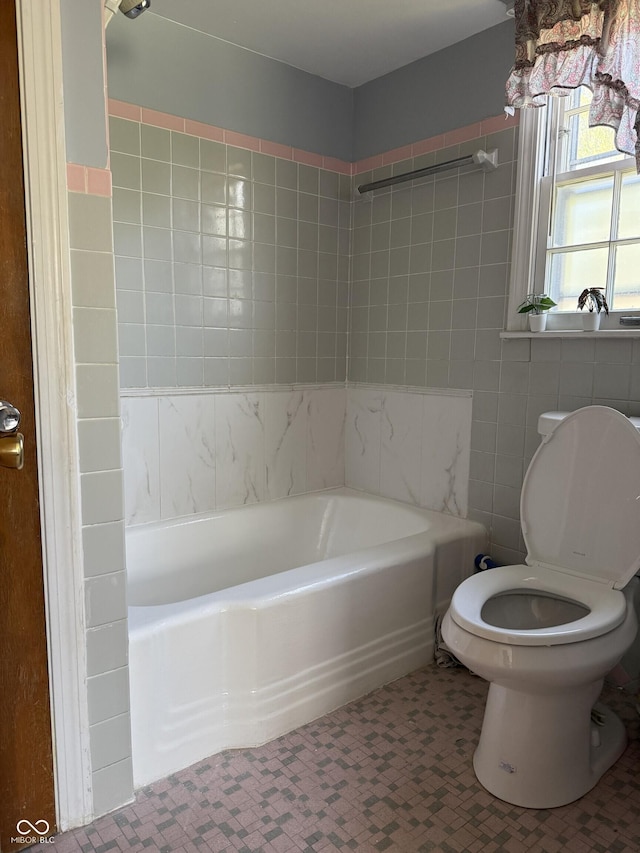 full bathroom with tile walls, bathing tub / shower combination, and toilet