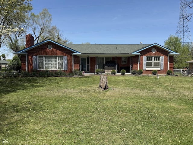 ranch-style house featuring a chimney, brick siding, and a front yard