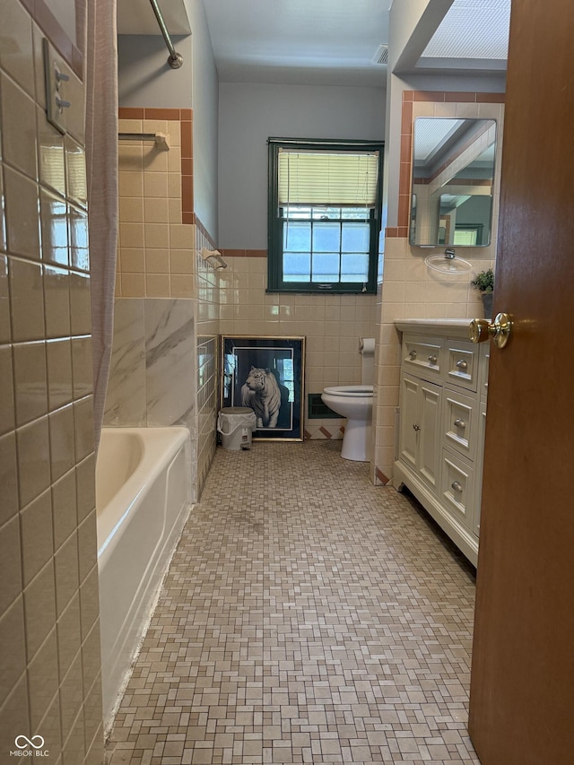 full bath with vanity, tile walls, a wainscoted wall, toilet, and visible vents