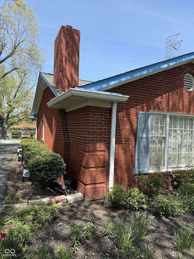 view of home's exterior with brick siding and a chimney