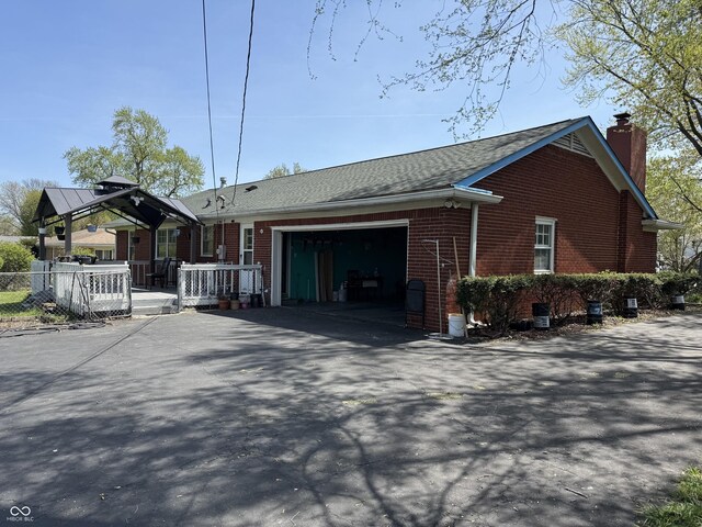 view of front facade with a gazebo, a chimney, driveway, a garage, and brick siding