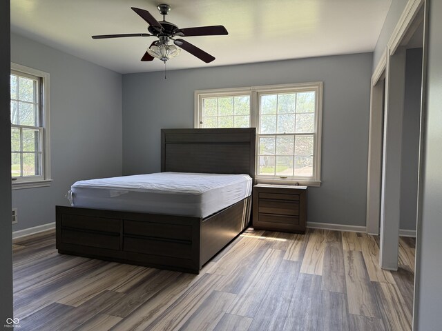 bedroom featuring ceiling fan, baseboards, and light wood-style flooring