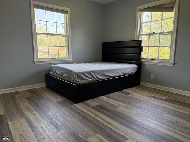bedroom featuring baseboards, multiple windows, and wood finished floors