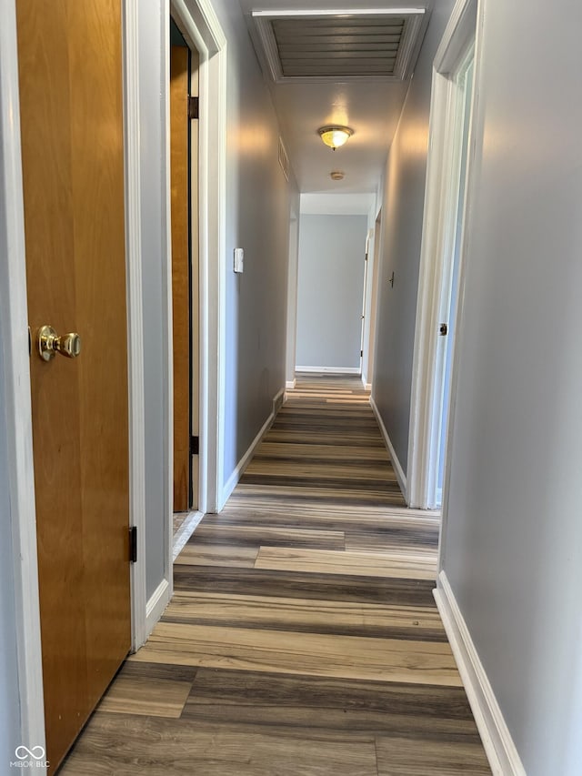corridor featuring baseboards, wood finished floors, and visible vents