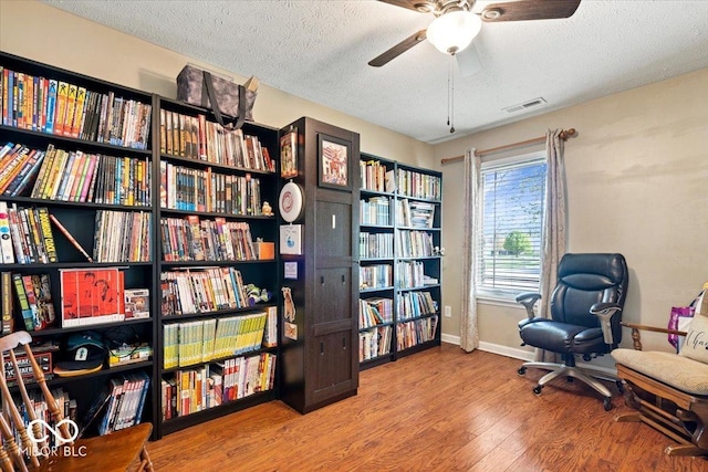 sitting room featuring visible vents, a ceiling fan, a textured ceiling, and wood finished floors