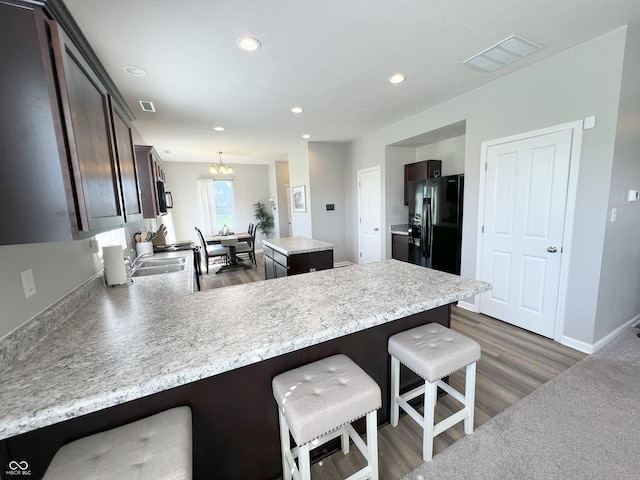 4245 W Fork Dr, Westfield, IN 46062 - kitchen with dark brown cabinetry, a peninsula, a kitchen island, dark wood-style flooring, and light countertops