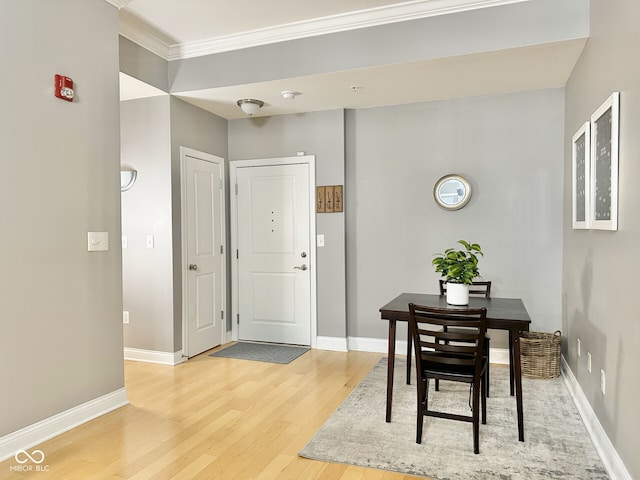 dining space with light wood-type flooring, crown molding, and baseboards