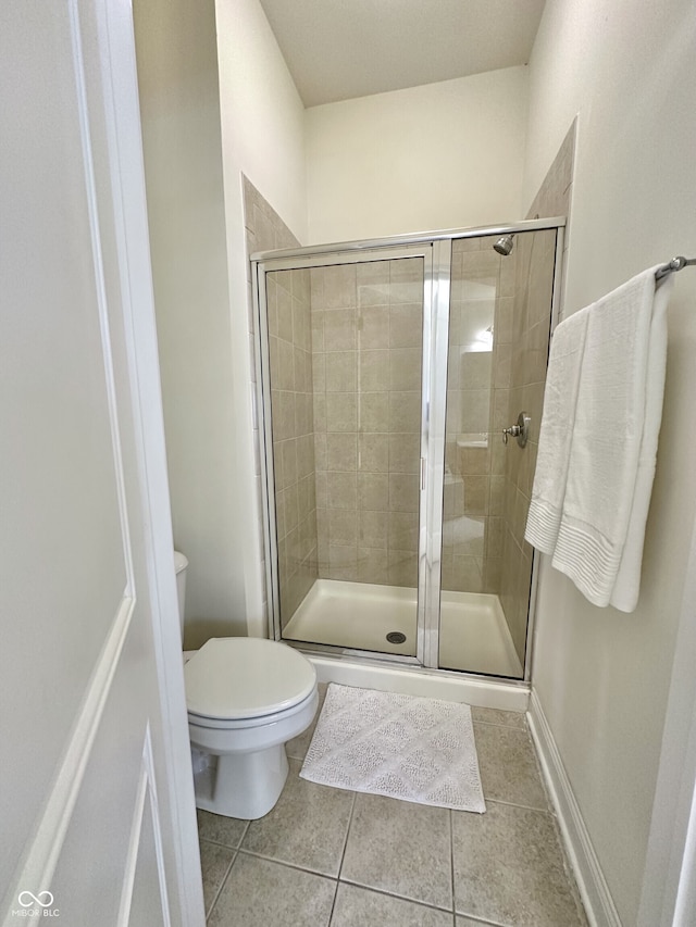 bathroom with a shower stall, toilet, and tile patterned flooring