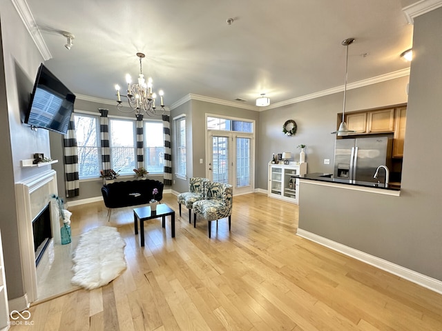 living room with a wealth of natural light, light wood-style floors, ornamental molding, and a chandelier