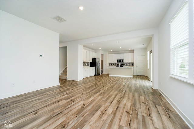 8654 Tripp Rd, Pendleton, IN 46064 - unfurnished living room featuring light wood-style floors, recessed lighting, baseboards, and stairway