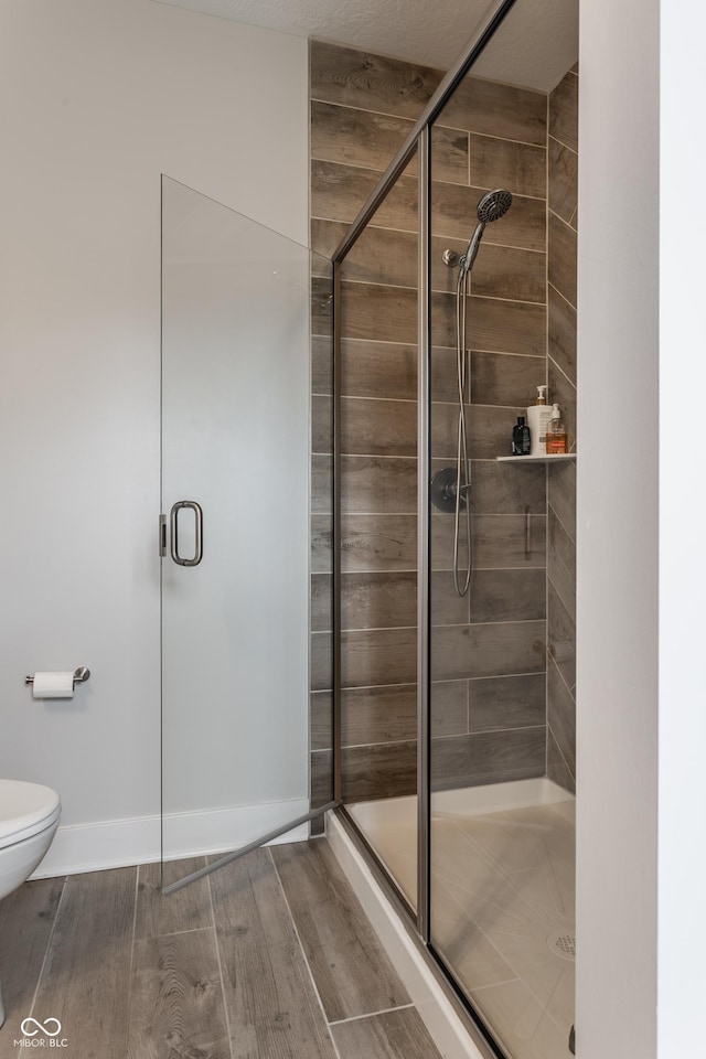 full bathroom with toilet, wood finished floors, and a shower stall