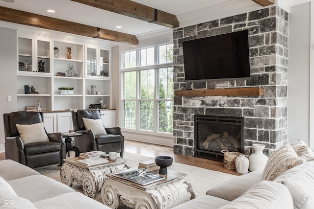 living area featuring beam ceiling, recessed lighting, ornamental molding, a fireplace, and wood finished floors