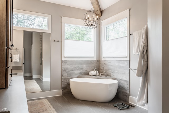 bathroom featuring tile patterned flooring, tile walls, a wealth of natural light, and a soaking tub