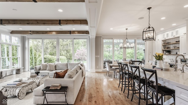 interior space featuring a chandelier, light wood-style floors, beam ceiling, recessed lighting, and ornamental molding
