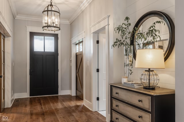 entryway featuring dark wood-type flooring, ornamental molding, a notable chandelier, and baseboards