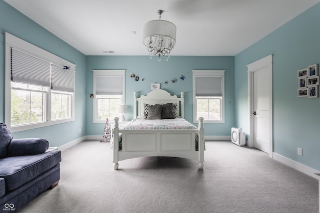 bedroom with an inviting chandelier, light carpet, multiple windows, and baseboards
