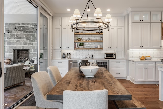 dining area with a chandelier, a fireplace, wine cooler, a toaster, and wood finished floors