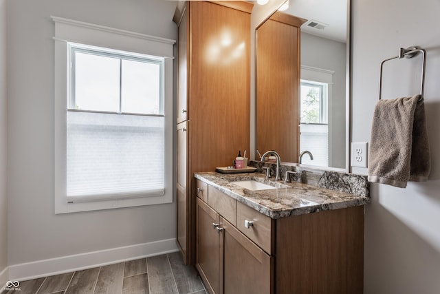 bathroom with wood finished floors, visible vents, vanity, and baseboards