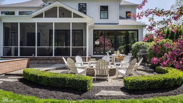 back of property featuring an outdoor fire pit, a shingled roof, a sunroom, and a patio area