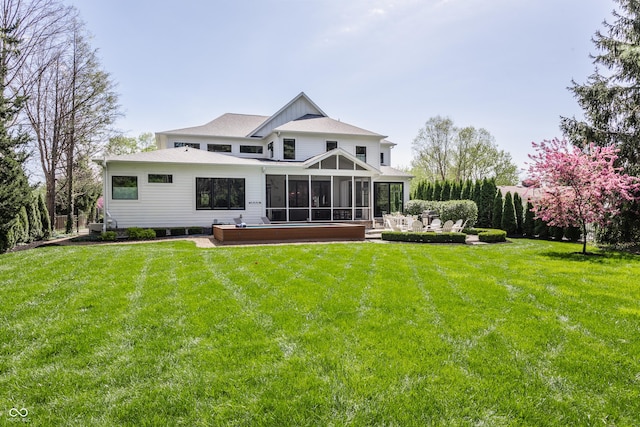 back of house featuring a lawn and a sunroom