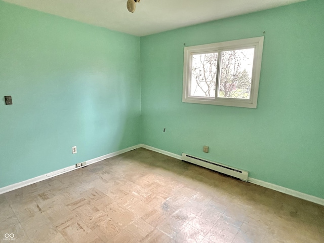unfurnished room featuring a baseboard heating unit and baseboards