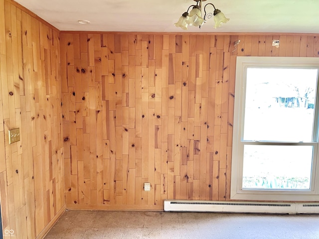 unfurnished room featuring a chandelier, wood walls, and baseboard heating