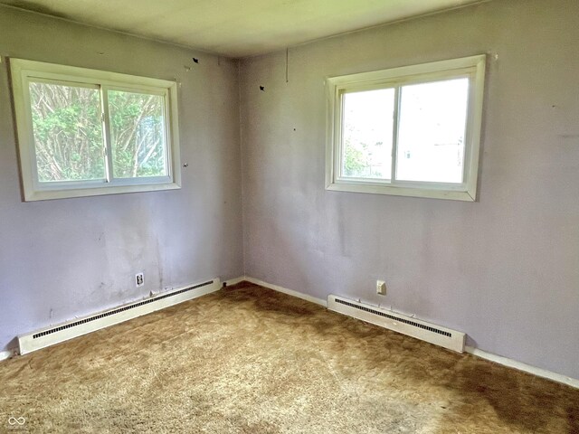 carpeted empty room with a baseboard heating unit, a wealth of natural light, and baseboards