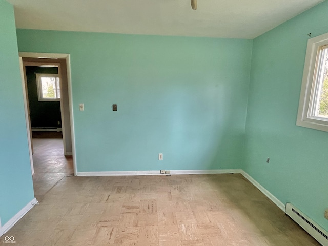 empty room featuring baseboards, baseboard heating, and plenty of natural light