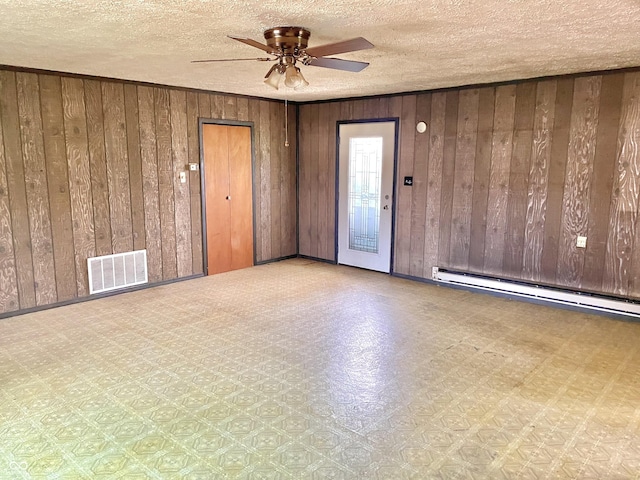 unfurnished room featuring wood walls, a ceiling fan, and visible vents